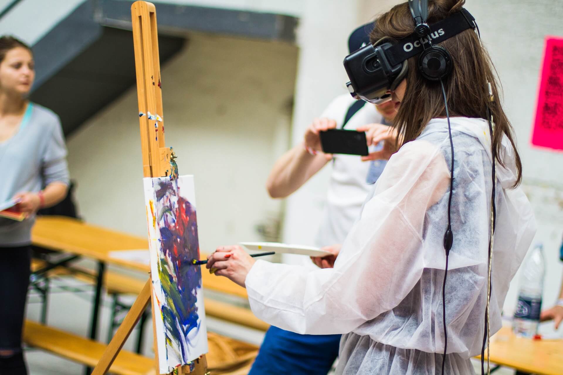 A girl painting on a canvas with a VR headset on